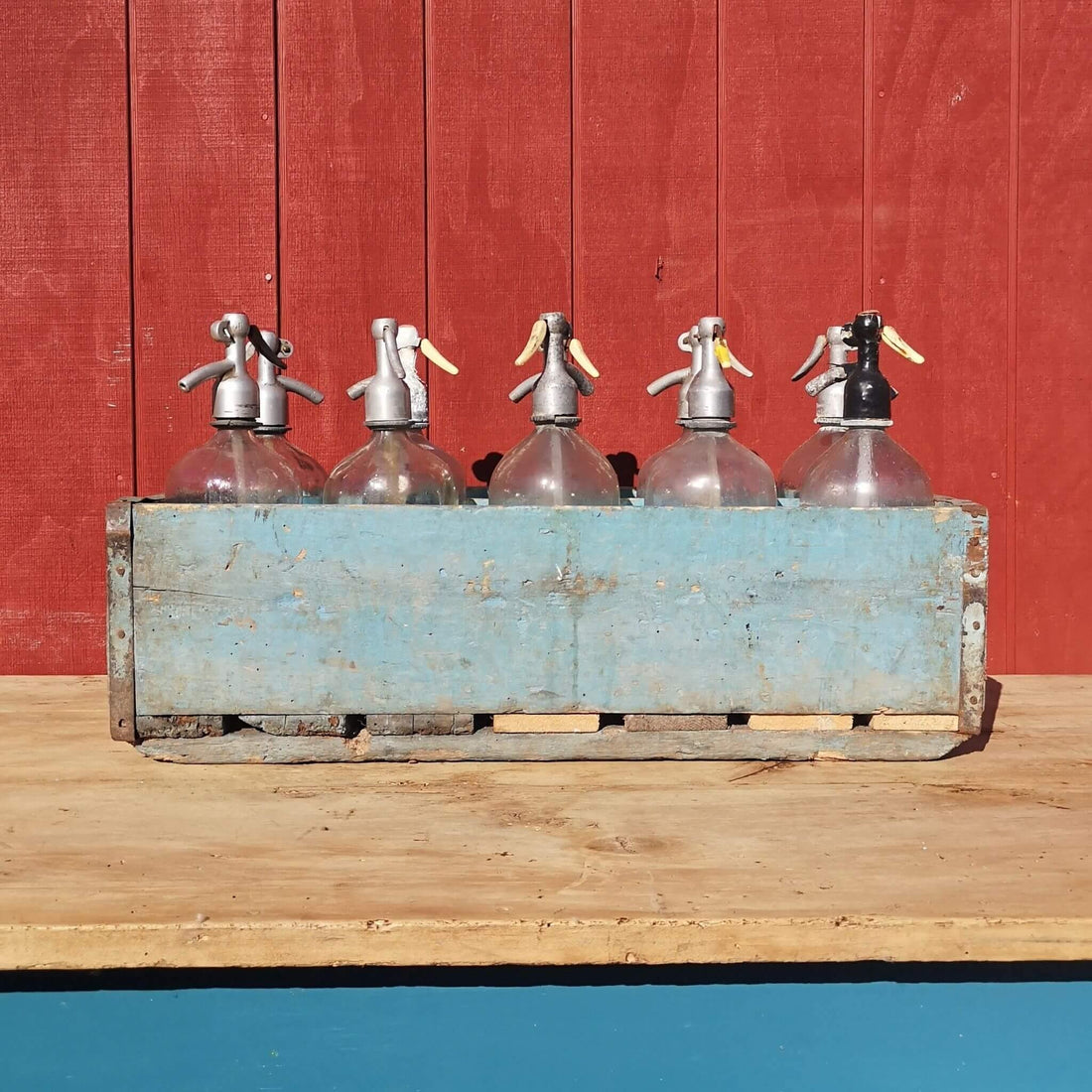 10 soda syphons in a crate