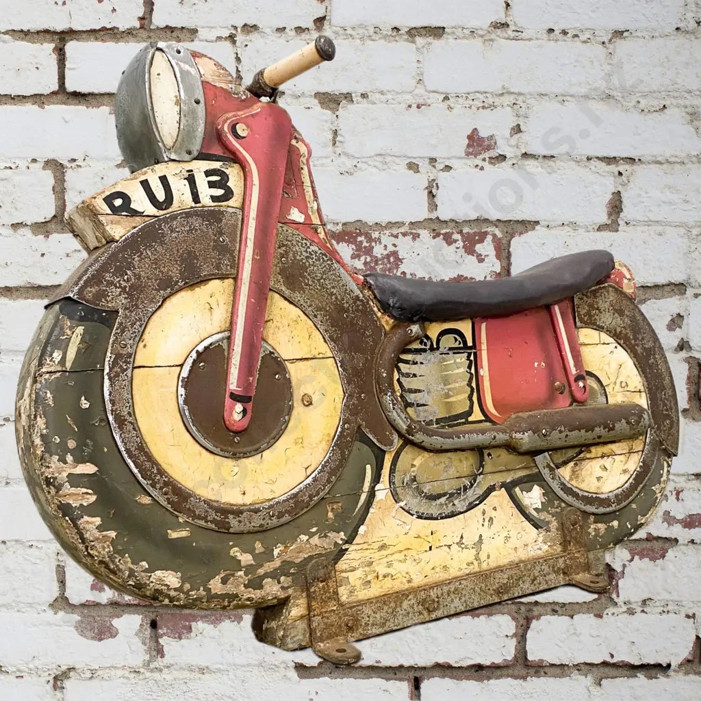 A hand painted motorcycle from a Merry-Go-Round. Made from wood with metal exhaust, headlight and fenders, seat has been recovered. Condition good.